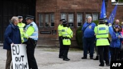 A lone pro-Brexit demonstrator, left, stands opposite anti-Brexit protesters outside Thornton Manor Hotel, Oct. 10, 2019, where Britain's Prime Minister Boris Johnson and Ireland's Prime Minister Leo Varadkar were meeting for Brexit talks.