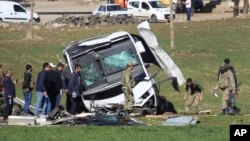 FILE - Members of Turkish forces gather around a bus that was destroyed in an explosion on the road linking the cities of Diyarbakir and Bingol, in southeastern Turkey, Feb. 18, 2016. Turkish police arrested 10 suspected Islamic State members in raids Thursday in the area.