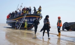 A group of people thought to be migrants crossing from France, come ashore aboard the local lifeboat at Dungeness, southern England, July 20, 2021.