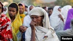 FILE - A woman stands in line with others to receive food donations at a school, which was turned into a temporary shelter for people displaced by conflict, in the town of Shire, in Ethiopia's Tigray region, March 15, 2021.