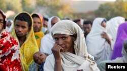 Seorang perempuan berdiri di tengah sekumpulan orang yang sedang mengantri untuk menerima donasi makanan di salah satu sekolah yang dijadikan tempat pengungsian di Kota Shire, Tigray, Ethiopia, pada15 Maret 2021. (Foto: Reuters/Baz Ratner)