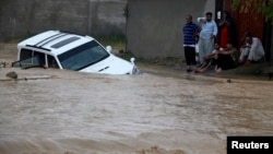 Family members wait for rescue workers after their vehicle was submerged in flood waters on the outskirts of Karachi, Pakistan, August 4, 2013. 