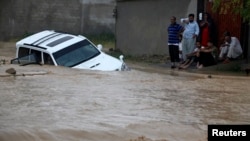 파키스탄 카라치에서 4일 폭우로 불어난 물에 차가 빠진 가운데, 탑승자들이 구조를 기다리고 있다.