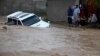 Family members wait for rescue workers after their vehicle was submerged in flood waters on the outskirts of Karachi, Pakistan, August 4, 2013. 