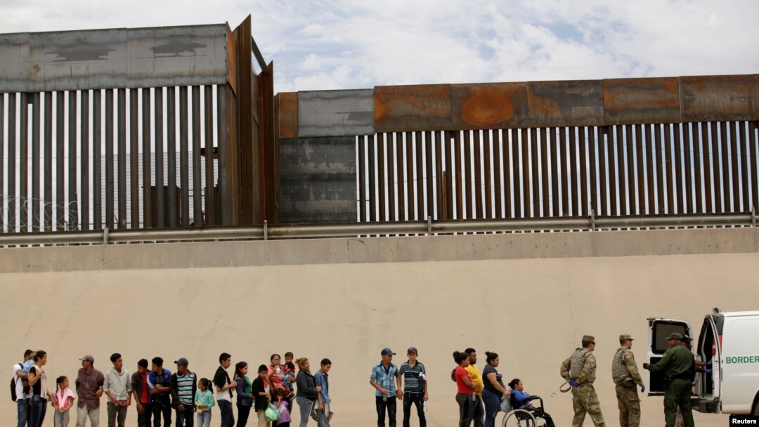 FILE - Members of the Border Patrol and U.S. military talk with migrants who illegally crossed the border between Mexico and the U.S. to request political asylum, as seen from Ciudad Juarez, Mexico, July 6, 2019. 
