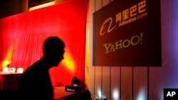 Foto Achiv: Yon moun mache bo kote yon ekran ki gen logo Yahoo ak Alibaba sou li nan vil Peken, an Chinn.