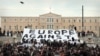 Para aktivis membentangkan spanduk bertuliskan "Eropa Menentang Neo-Nazi" dalam sebuah protes di depan Parlemen Yunani pada 15 Desember 2021 untuk menentang rasisme.(Foto: AFP/Louisa Gouliamaki)