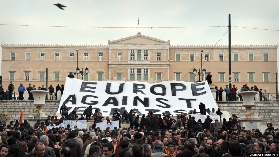 Para aktivis membentangkan spanduk bertuliskan "Eropa Menentang Neo-Nazi" dalam sebuah protes di depan Parlemen Yunani pada 15 Desember 2021 untuk menentang rasisme.(Foto: AFP/Louisa Gouliamaki)