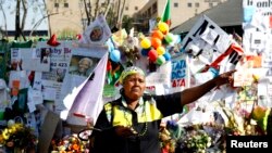 A well wisher wearing ANC colors gestures in front of the Medi-Clinic Heart Hospital, where the ailing former South African President Nelson Mandela is being treated at, in Pretoria, July 9, 2013. 