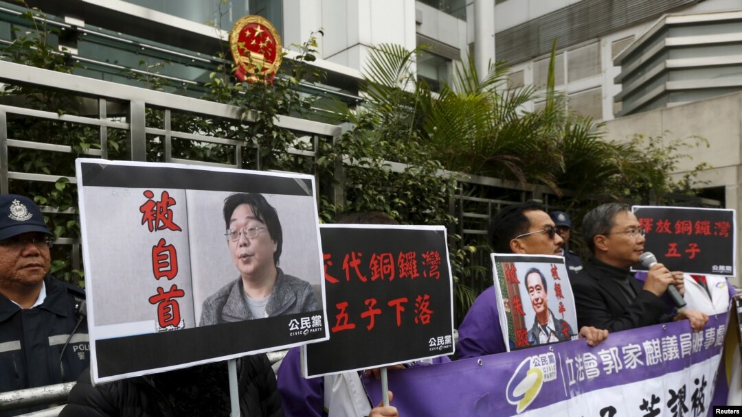 香港民主抗议者举着铜锣湾书店老板桂民海（左）和李波（右）的肖像（2016年1月19日）。