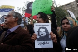 FILE - Human rights activists hold a picture of Salman Haider, who was missing, during a protest to condemn the disappearances of social media activists in Karachi, Pakistan, Jan. 19, 2017. Haider returned home, more than 20 days after disappearing in Islamabad.