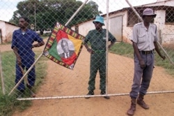 FILE: Police (R) and black squatters (behind the gate) guard the farm of expelled white farmer Rob Marshell, in Mazowe, some 60 km north of Harare, Zimbabwe, April 10, 2000.