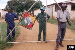 Police (R) and black squatters (behind the gate) guard the farm of expelled white farmer Rob Marshell, in Mazowe, some 60 km north of Harare, Zimbabwe, April 10, 2000.