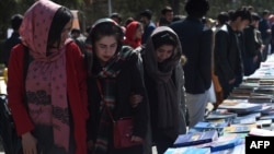 FILE - Visitors browse a book exhibition to mark International Women's Day at Kabul University, March 8, 2020. The Taliban say women have nothing to fear under their rule, but that's not how many educated Afghan women see it.
