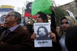 FILE - Human rights activists hold a picture of Salman Haider, who is missing, during a protest to condemn the disappearances of social activists in Karachi, Pakistan, Jan. 19, 2017.