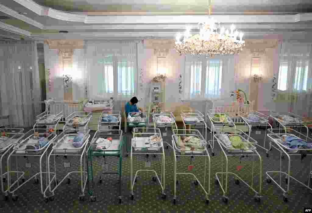 A nurse cares for newborn babies at Kyiv&#39;s Venice hotel in Ukraine. More than 100 babies born to surrogate mothers have been stranded in Ukraine as their foreign parents cannot collect them due to border closures imposed during the coronavirus pandemic.