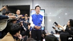 South Korea's main opposition Democratic Party leader Lee Jae-myung, center, speaks to reporters after watching TV broadcasting results of exit polls for the parliamentary election at the National Assembly on April 10, 2024, in Seoul, South Korea. 
