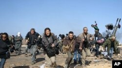 Journalists and photographers, including Hicks (R- in glasses) and Addario (far L), Moore (2nd L), Pickett (3rdL) and Poupin (4th L) run for cover during a bombing run by Libyan government planes at a checkpoint near the oil refinery of Ras Lanuf March 11