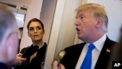 President Donald Trump, accompanied by White House Communications Director Hope Hicks, second from left, speaks to reporters aboard Air Force One in Manila, Nov. 14, 2017.