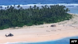This handout photo taken Aug. 2, 2020 and released Aug, 4, 2020, by the Australian Defense Force shows an Australian Army helicopter landing near "SOS" signage on a beach on Pikelot Island where three missing sailors were found in good condition.