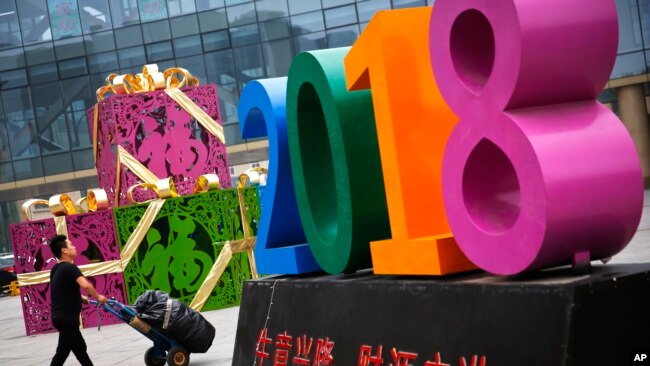 北京一家零售和批发商场大楼前写有“生意兴隆，财源广进“字样的商场装饰物。 （2018年7月9日）