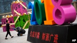 A man pushes a cart loaded with goods past a decoration baring the words "Business Prospers and Booming" outside a retail and wholesale clothing mall in Beijing, China, July 9, 2018.