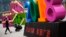 A man pushes a cart loaded with goods past a decoration baring the words "Business Prospers and Booming" outside a retail and wholesale clothing mall in Beijing, China, July 9, 2018.