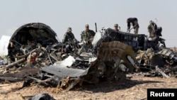 Military investigators from Russia stand near the debris of a Russian airliner at the site of its crash at the Hassana area in Arish city, north Egypt, Nov. 1, 2015.