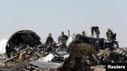 Military investigators from Russia stand near the debris of a Russian airliner at the site of its crash at the Hassana area in Arish city, north Egypt, Nov. 1, 2015.