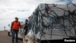 Para pekerja usai menurunkan kiriman pertama vaksin COVID-19, Sputnik V, buatan Rusia di Bandara Internasional Caracas, Venezuale, 13 Februari 2021. (Foto: Reuters)