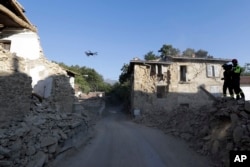 Firefighters operate a drone to survey quake-damaged buildings in the village of Cossito, central Italy, Aug. 27, 2016.