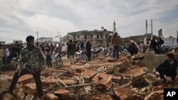 Syrians wait alongside rubble in Maaret Misreen near Idlib to buy bread at a local bakery, December 12. (AP)