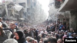 Residents wait to receive food aid distributed by the U.N. Relief and Works Agency (UNRWA) at the besieged al-Yarmouk camp, south of Damascus on January 31, 2014.
