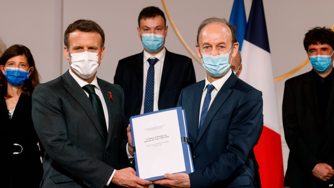 Historian and Commission chief on the France's role in 1994's Rwandan genocide, Vincent Duclert, right, gives a report to French President Emmanuel Macron, at the Elysee Palace, in Paris, March 26, 2021. 