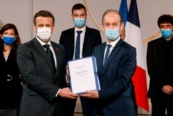 FILE - Historian and Commission chief on France's role in 1994's Rwandan genocide, Vincent Duclert, right, presents a report to French President Emmanuel Macron, at the Elysee Palace, in Paris, March 26, 2021.