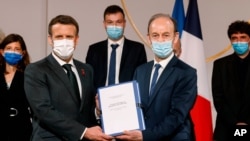 Historian and Commission chief on France's role in 1994's Rwandan genocide, Vincent Duclert, right, gives a report to French President Emmanuel Macron, at the Elysee Palace, in Paris, March 26, 2021.