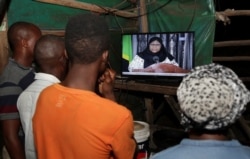 Residents watch the television announcement of the death of Tanzania's President John Magufuli, addressed by Vice President Samia Suluhu Hassan in Dar es Salaam, Tanzania, March 18, 2021.