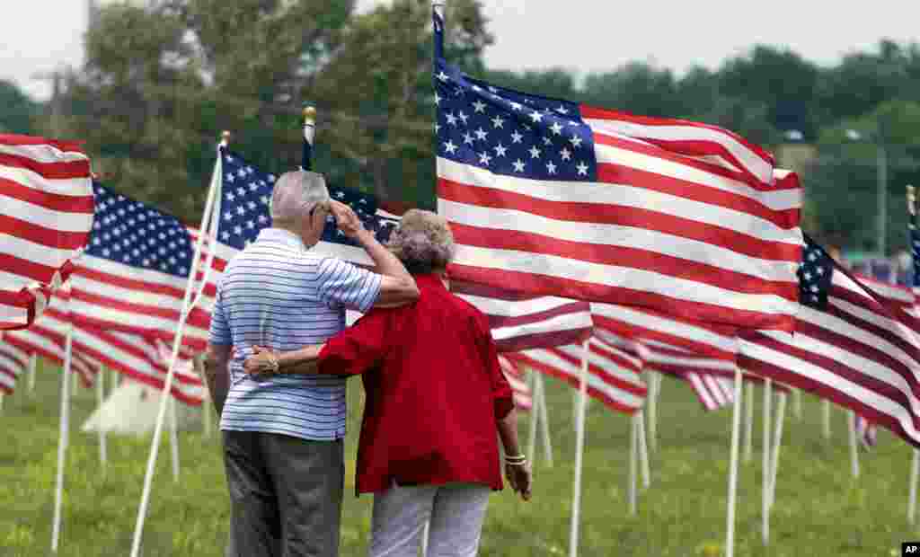 World War II veteran Jesse R. Turner salutes while being comforted by Helen Marie Misel at a display of more than 1700 United States flags in Shawnee, Kan., May 26, 2012. 
