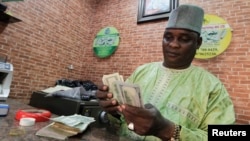 FILE - A bureau de change operator counts U.S. currency notes in Abuja, March 12, 2015. 