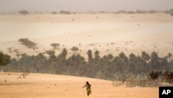 FILE - A young girl carries an empty container as she walks across the sands to fill it from a well in Barrah, a desert village in the Sahel belt of Chad.
