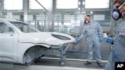 FILE - Workers lacquer Porsche Macan car body in Leipzig, Germany, Feb. 11, 2014.