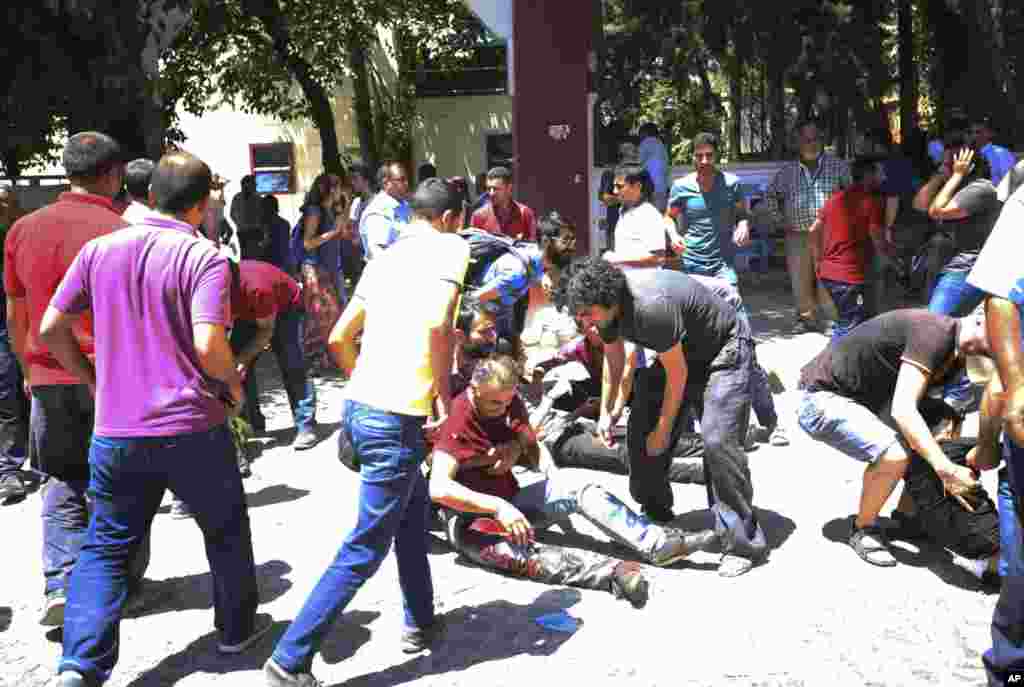 People help the wounded after an explosion in the southeastern Turkish city of Suruc near the Syrian border, July 20, 2015.