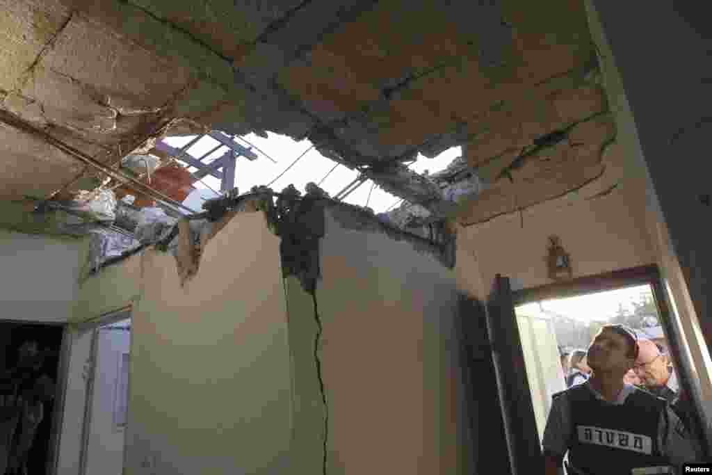 An Israeli police officer looks at the damage to a house after a rocket fired by Palestinian militants in Gaza landed in the southern town of Ofakim November 18, 2012. Israel bombed Palestinian militant targets in the Gaza Strip from air and sea for a fif