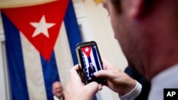 A visitor poses for a photograph in front of the last Cuban flag that was lowered from the Cuban Embassy in Washington on Jan. 3, 1961, when relations between the United States and Cuba were severed, in their new embassy in Washington, July 20, 2015.