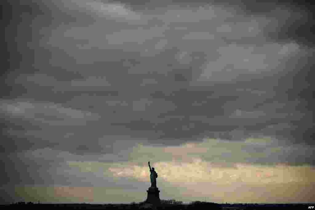 Langit mendung tampak di atas Patung Liberty terlihat dari kapal feri Staten Island dekat New York City, AS.