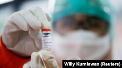Seorang petugas kesehatan menunjukkan satu dosis vaksin COVID-19 buatan Sinovac di sebuah puskemas di Jakarta, 14 Januari 2021. (Foto: Willy Kurniawan/Reuters)