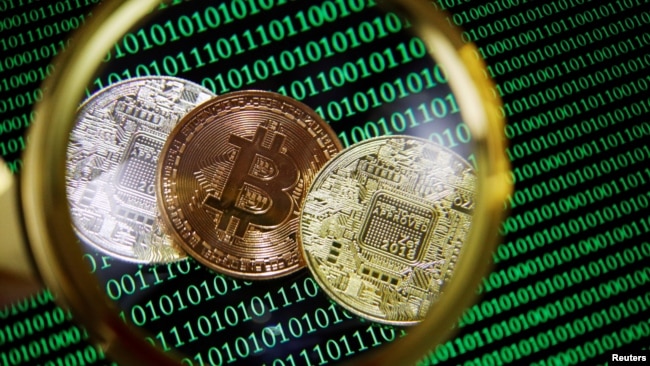 FILE PHOTO: Representations of Bitcoin and other cryptocurrencies on a screen showing binary codes are seen through a magnifying glass in this illustration picture taken Sept. 27, 2021.