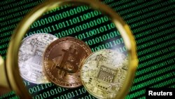 FILE: Representations of Bitcoin and other cryptocurrencies on a screen showing binary codes are seen through a magnifying glass. Taken Sept. 27, 2021.