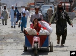 FILE - Afghan families arrive at the border crossing in Torkham, June 18, 2016.