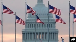 FILE - An early morning runner crosses in front of the U.S. Capitol as he passes the flags circling the Washington Monument in Washington, Sept. 27, 2017.